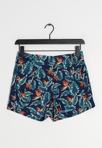 Marineblauwe shorts met een tropisch bloemenpatroon, voorzien van grote groene bladeren en oranje vogels van het paradijs. Glad stof, relaxed fit.