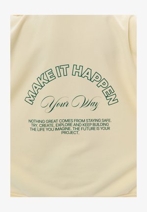 Tekst op beige stof: "LAAT HET GEBEUREN Op jouw manier. Niets groots komt voort uit veilig blijven. Probeer, creëer, ontdek en blijf het leven bouwen dat je voorstelt."