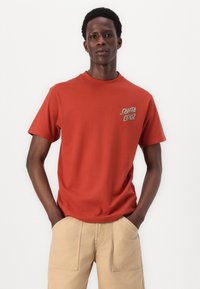 Red cotton t-shirt with short sleeves and crew neckline; features a small "Santa Cruz" logo printed on the left chest.