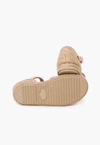 Kootud tan värvi espadrillid lame, tekstureeritud tallaga. Ülemine osa on valmistatud looduslikest kiududest ning suletav on ühtne pannal.