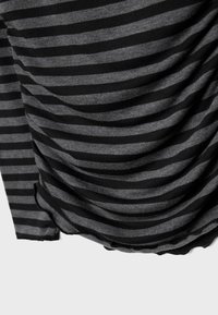 Tessuto a righe nere e grigie con trama rugosa. Morbido cotone, caratterizzato da strisce orizzontali e un bordo inferiore ondulato.