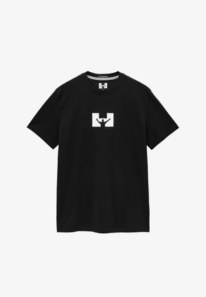 Maglietta nera in cotone con un design grafico bianco che raffigura una persona con le braccia sollevate all'interno di un rettangolo stilizzato. Maniche corte e collo a giro.