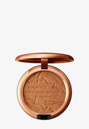Bronzefarbener Kompaktpuder mit eingeprägtem Text in einem runden, roségoldfarbenen Metallgehäuse mit offenem Scharnierdeckel.