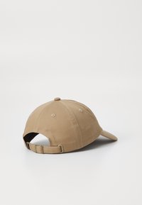 Beige bomulds hat med en buet skygge, justerbar rem bagpå og ventilationshuller, med et enkelt design og glat tekstur.