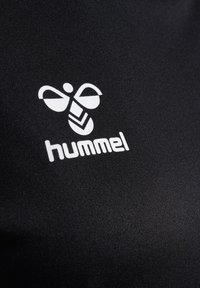 Black textile featuring a white brand logo of Hummel, with distinct bee-like design elements and geometric accents.