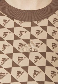 Hnědá a béžová mikina s vzorem, ribbovaným výstřihem, která obsahuje diamantový motiv a vyšitým logem Adidas uprostřed.