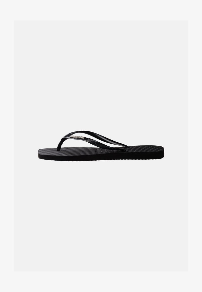 Černá gumová žabky s texturovanou podrážkou a tenkými Y-tvarovanými pásky, pohled ze strany na jednobarevném pozadí.