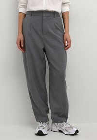 Pantalons gris taille haute en tissu doux, avec des plis, une coupe ajustée et une jambe droite, associés à des baskets blanches.
