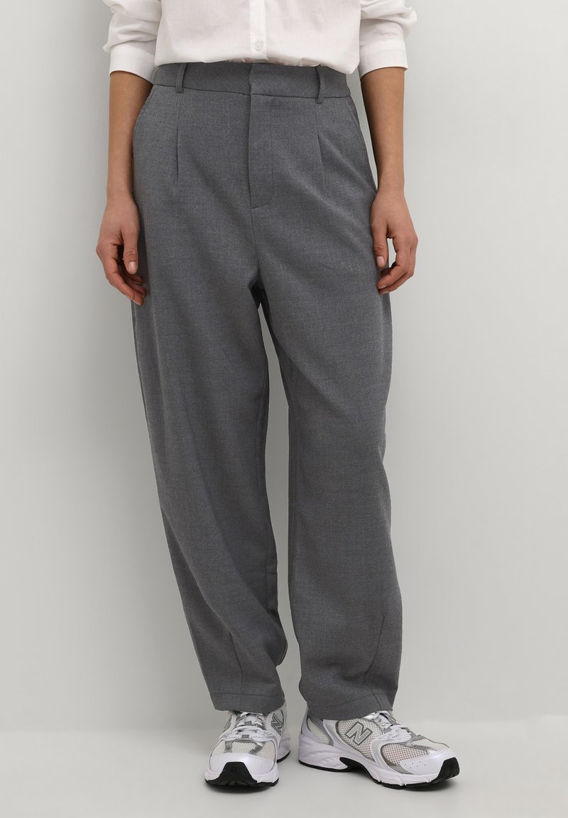Pantalons gris taille haute en tissu doux, avec des plis, une coupe ajustée et une jambe droite, associés à des baskets blanches.