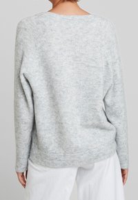 Hellgrauer Pullover mit weicher Textur, geripptem Saum und abgefallenen Schulternähten, der einen entspannten Sitz und ein minimalistisches Design aufweist.