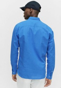 Blauw overhemd met lange mouwen van katoen, voorzien van een klassieke kraag, met knopen afgewerkt manchetten en een losse pasvorm met subtiele textuur en stikseldetails.