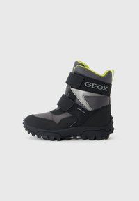 Bottes imperméables noires et grises avec des accents jaunes. Comprend deux sangles Velcro, une semelle robuste et un col rembourré.