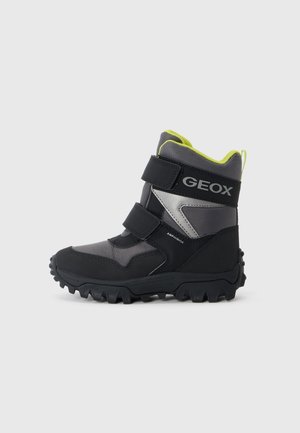 Bottes imperméables noires et grises avec des accents jaunes. Comprend deux sangles Velcro, une semelle robuste et un col rembourré.