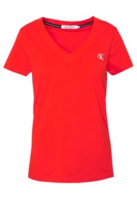 Červené bavlněné tričko s výstřihem do V, krátkými rukávy a malým bílým výšivkovým logem na levé části hrudi. Hladká textura po celé ploše.