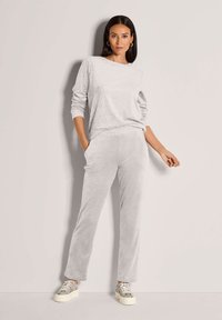 Lichtgrijze, gestructureerde sweatshirt met een luipaardprint en lange mouwen, gecombineerd met zachte grijze sweatpants met rechte pijpen en sneakers met patroon.