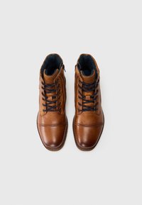 Bottes de cheville en cuir marron avec une finition lisse, un design lacé et des accents bleu marine. Comprend une fermeture éclair et un intérieur rembourré.