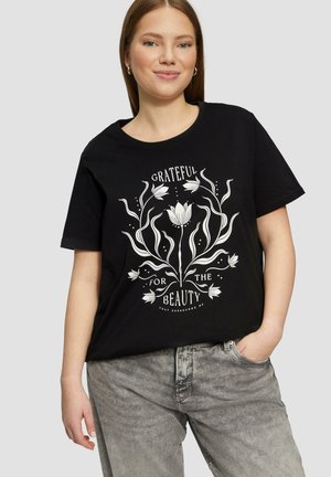 T-shirt en coton noir arborant un design graphique textuel floral blanc portant l'inscription « RECONNAISSANT POUR LA BEAUTÉ » entouré de lignes et de points.