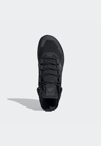 Sort sportssko med en tekstureret mesh-overdel, vinkelret design, reflekterende detaljer og snørebåndsclosure. Frontvinkel, der fremhæver formen.
