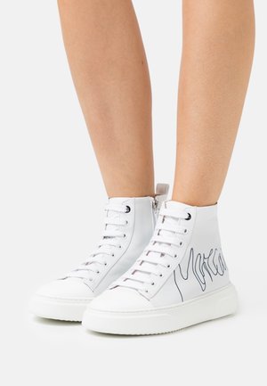 Zapatillas altas blancas de cuero, con una textura suave, costuras negras y una cremallera lateral, con el texto "More" en un diseño cursivo.