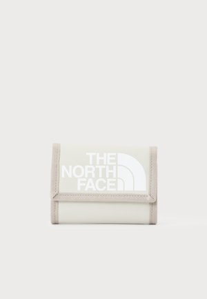Cartera beige plegada con ribete beige y logo "The North Face" impreso en blanco en la solapa frontal, sobre un fondo liso.