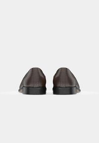 Brune lærstøvler med en glat overflade, rund tå og lav sort gummikile. Minimalistisk design med subtile syninger.