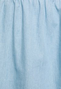 Falda de mezclilla azul clara con una cinturilla fruncida, que presenta una textura suave y variaciones sutiles en el tono a lo largo de la tela.