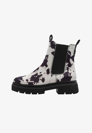 Chelsea boot noir et blanc à pois avec un dessus texturé, panneau latéral élastique et semelle épaisse noire. Tirette renfoncée à l'arrière.