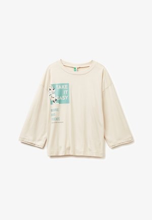 Camisa de manga larga color crema con el texto "Tómalo con calma", un gráfico de Minnie Mouse y texto adicional que dice "Minnie y sus amigos".