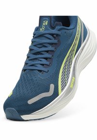 Scarpa da corsa in rete blu con accenti grigi e giallo neon; presenta una punta arrotondata, colletto imbottito e suola testurizzata per la presa.