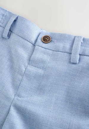 Lyseblåt denimstof med en glat tekstur, der har en brun knaplukning og bæltestropper, syningsdetaljer og en sidelomme.