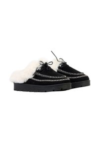 Chaussures en daim noir avec doublure en fourrure blanche, présentant des coutures décoratives et des semelles plates en caoutchouc noir. Lacées à l'avant avec des lacets noirs.