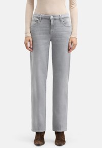Jasnoszare jeansy o prostych nogawkach z przednimi kieszeniami, delikatnym przetarciem i zapięciem na guzik. Połączone z brązowymi botkami za kostkę.