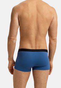 Herrarnas blå boxerkalsonger i mjukt tyg, med svart elastisk midjeband med präglad logotyp, figursydd design med medelhög skärning.