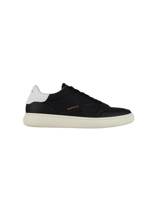 Zwarte lage sneaker met witte hielaccent, gouden "SMITH X" branding aan de zijkant en dikke off-white zool.