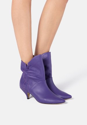 Stivali alla caviglia viola in pelle liscia. Presentano una punta affusolata, un design morbido e un tacco piccolo e appuntito.