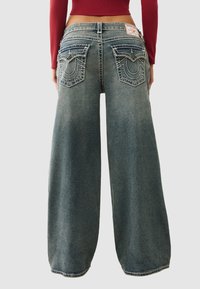 Dżinsy o szerokich nogawkach w wyblakłym niebieskim denimu, z wysokim stanem, misternym przeszyciem na tylnych kieszeniach oraz oznaczeniem marki na tylnej części pasa.