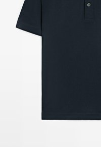 Dunkelmarineblaues Polohemd mit kurzen Ärmeln und Zweiknopf-Leiste, flach auf weißem Hintergrund liegend, links Ärmel und Saum sichtbar.