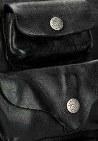 Borsa in pelle nera con due tasche frontali, ognuna con chiusura a scatto e hardware argento. Texture liscia con dettagli di grana sottile.