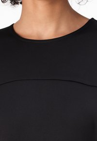 Top negru cu o textură netedă, decolteu rotund și un design subtil al cus�ăturii pe piept. Fără embellishments suplimentare.