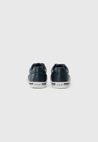 Mørkeblå lærersneakers med hvite såler, med diskrete stripete detaljer og preget logo på hælen. Klassisk lavt design.