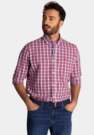Rood-blauw geruit overhemd met kraag, lange mouwen en een zak, gecombineerd met donkere denim jeans en een marineblauwe geweven riem.