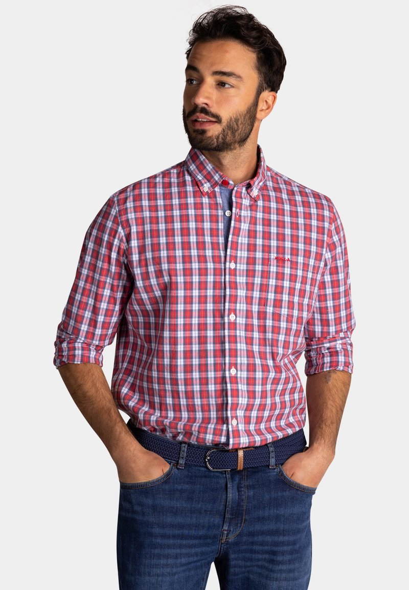 Rood-blauw geruit overhemd met kraag, lange mouwen en een zak, gecombineerd met donkere denim jeans en een marineblauwe geweven riem.