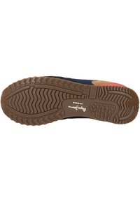 Sole tenisky z hnědé gumy, texturovaný vzor podrážky, detail loga a kontrastní námořnická svrchní část. Navrženo pro sportovní a volnočasové nošení.