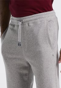 Graue Sweatpants mit weichem Material, elastischem Bund mit Kordelzügen und Seitentaschen; kleines Logo auf dem Oberschenkel.
