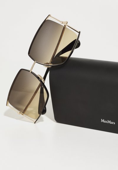 Occhiali da sole Max Mara con lenti oversize marroni sfumate, montatura in plastica nera e dettagli in tonalità oro. Include una custodia nera.