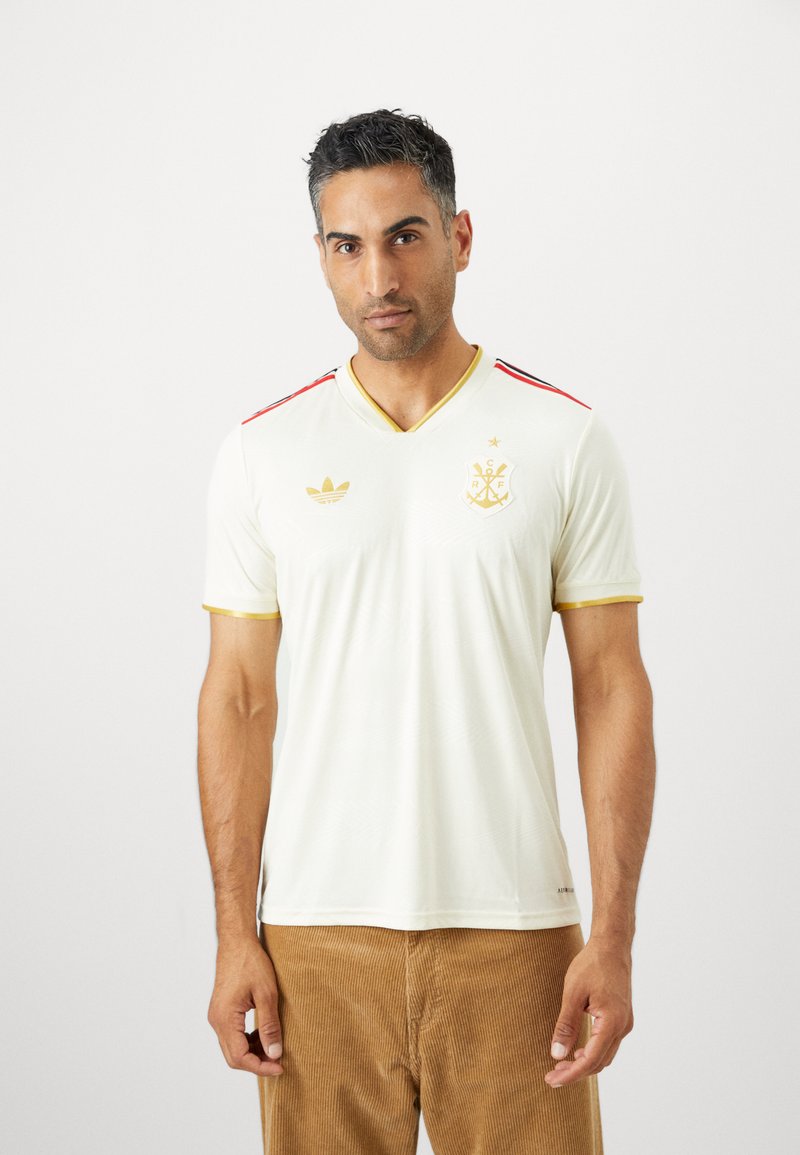 Weißes T-Shirt mit kurzen Ärmeln und V-Ausschnitt, roten und goldenen Akzenten an den Schultern sowie einem Logo auf der Brust. Hergestellt aus glattem, leichtem Stoff.