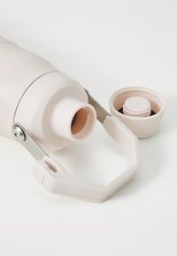 Light pink insulated water bottle with a silicone grip, stainless steel handle, and a removable lid featuring a small vent cap.