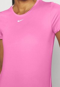 Camiseta atlética rosa hecha de una tela suave, con un cuello redondo y mangas cortas, con un logo blanco de Nike en el pecho.