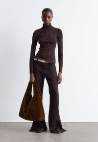 Braun gerippter Rollkragenpullover, eng anliegend; dunkelbraune Schlaghose; braune Kunstfelltasche; minimalistisches Design; glatte Textur; neutraler Hintergrund.