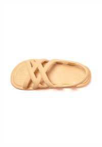 Beige sandal with a woven texture, featuring crisscross straps and a flat sole. The design provides open ventilation and a casual appearance.